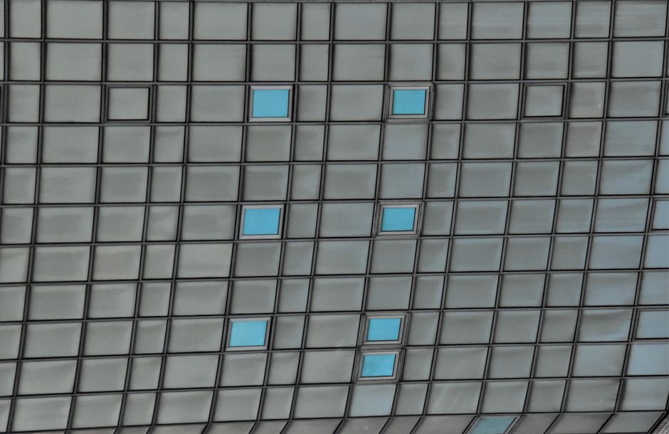 Facade of a modern building with geometric glass panels and blue windows.