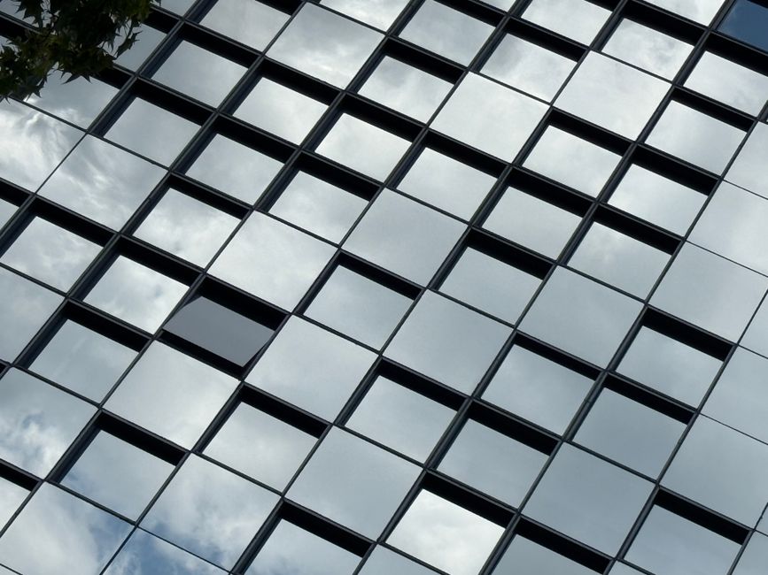 Abstract view of a building facade with mirrored glass squares reflecting the sky.