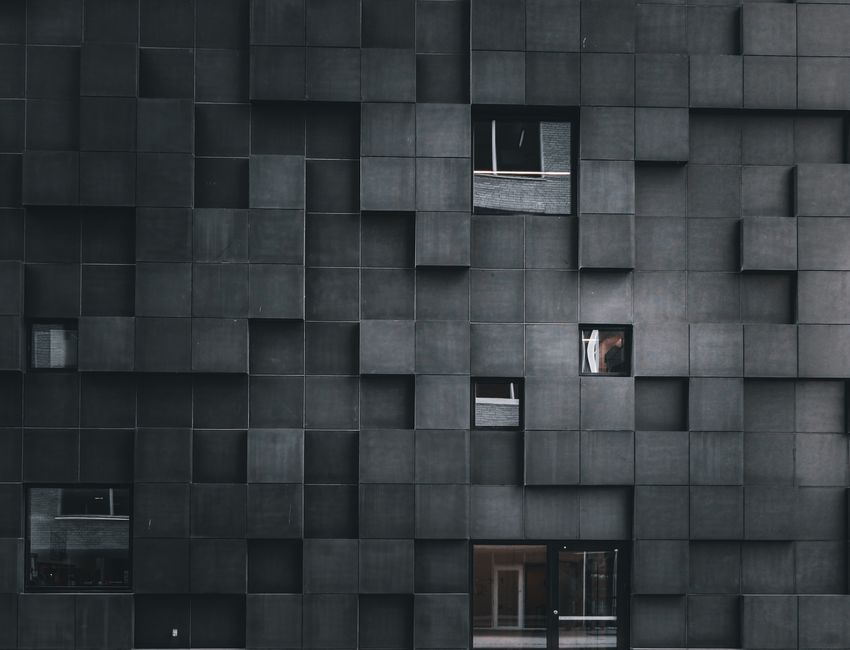 Modern architectural facade with geometric patterns and scattered windows.