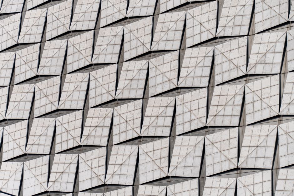An abstract view of a modern facade with a geometric pattern of square tiles creating visual depth.